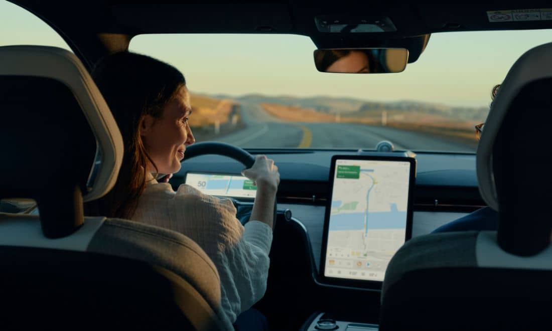 senhora a conduzir com um ecrã interativo no automóvel