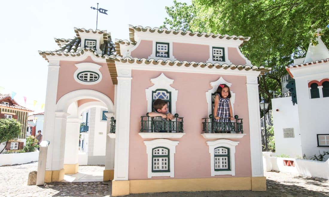 crianças à janela de uma casinha em miniatura no Portugal dos Pequenitos