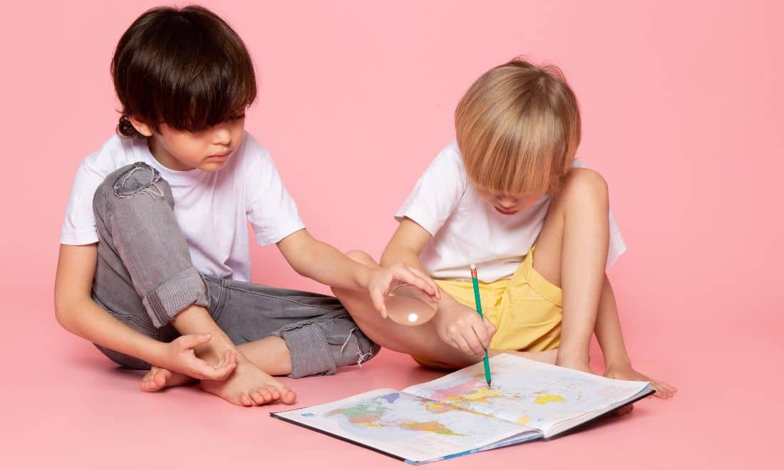 duas crianças sentadas no chão a pintar um mapa