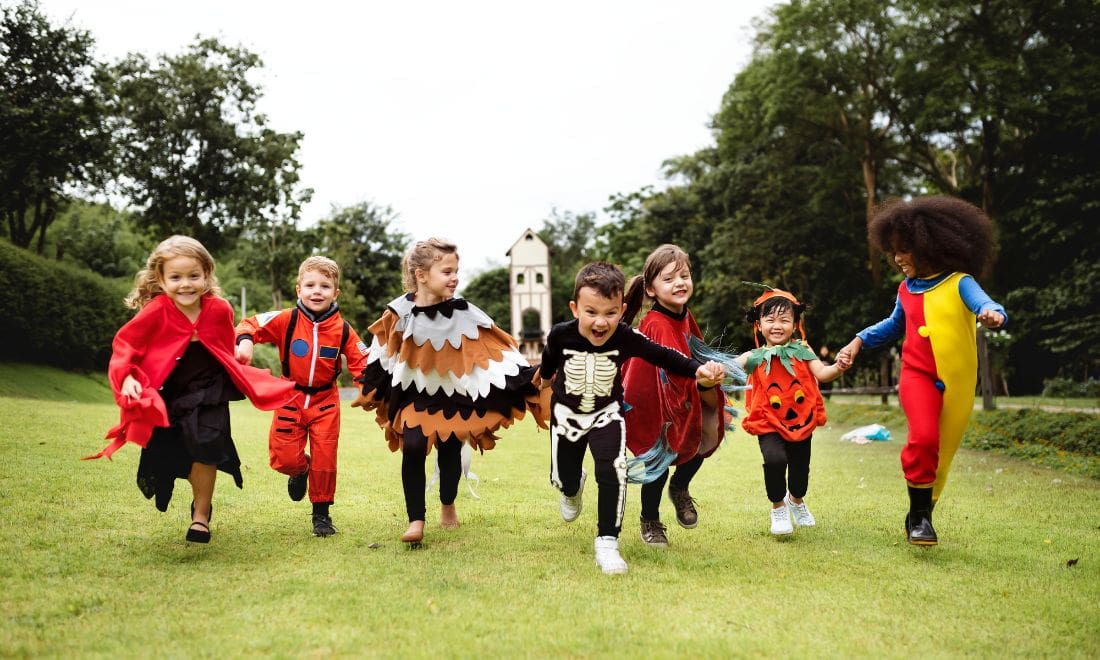 Crianças mascaradas a correr ao ar livre no Halloween