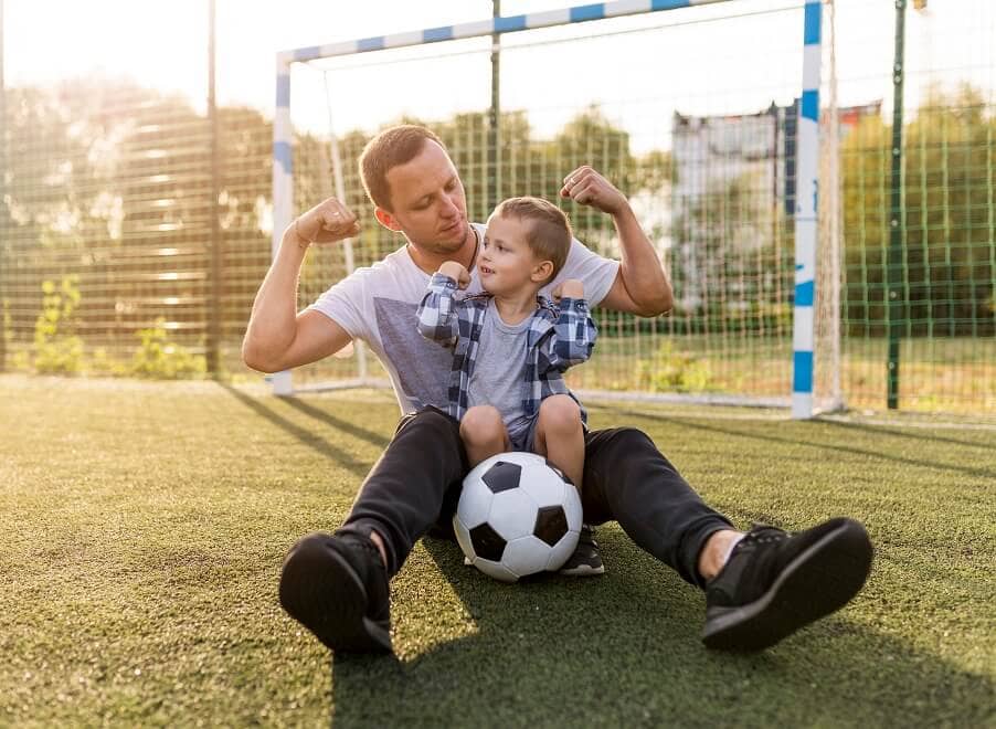 pai-e-filho-a-mostrar-musculos-no-campo-de-futebol-bola-geral