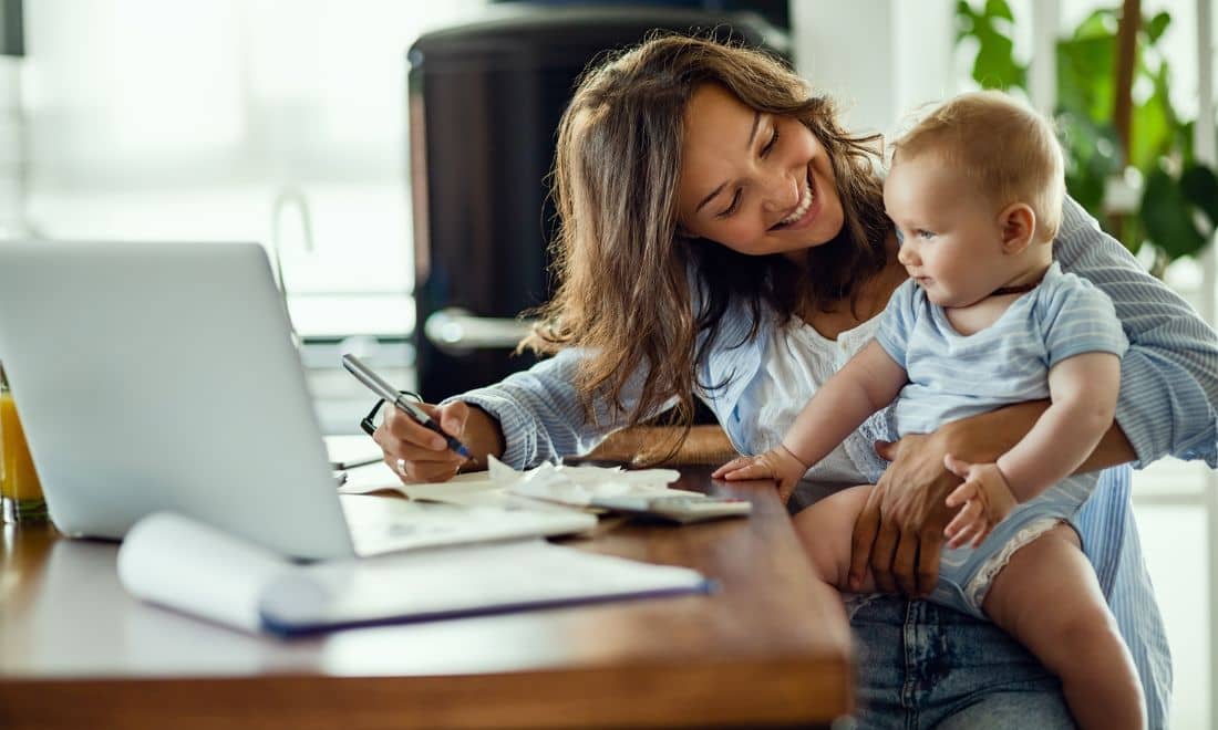 mãe com o bebé ao colo à frente do computador