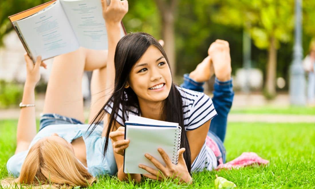 duas amigas a estudar na relva com cadernos