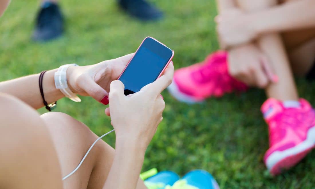 pessoa a usar um smartphone sentada na relva