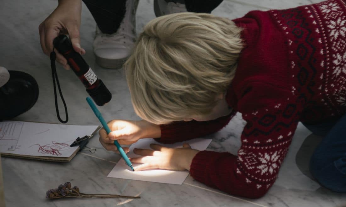 MACAM férias de Natal oficina de Natal para crianças menino a desenhar a mão no chão com lanterna e camisola de inverno