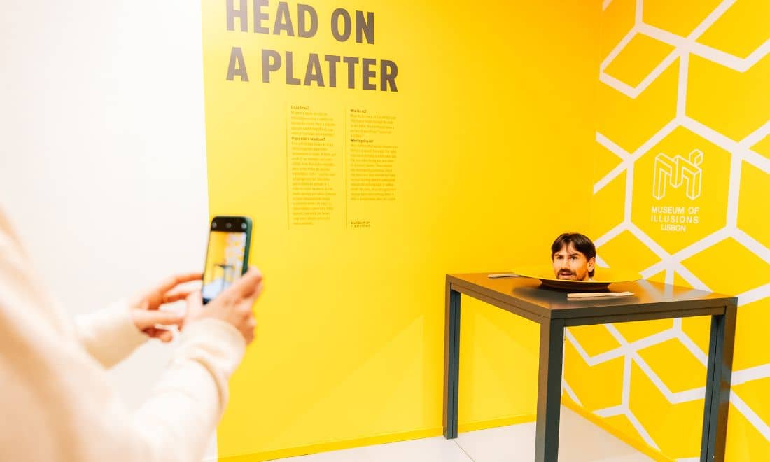 Museu das Ilusões cabeça na bandeja e telemóvel a tirar foto