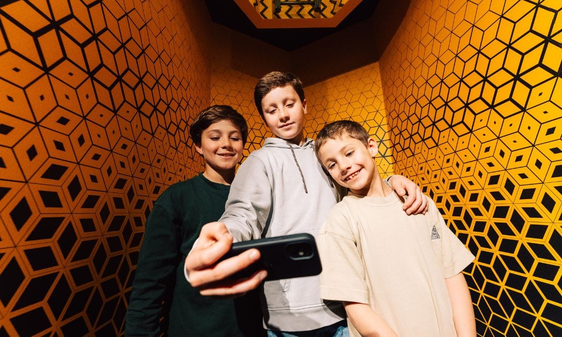 Museu das Ilusões três crianças meninos numa sala cor de laranja a tirar selfie