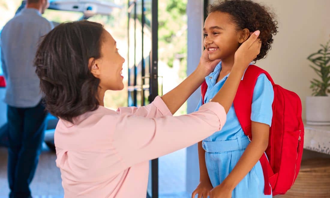 CA Vida menina com mochila vermelha às costas regresso às aulas e mãe à frente