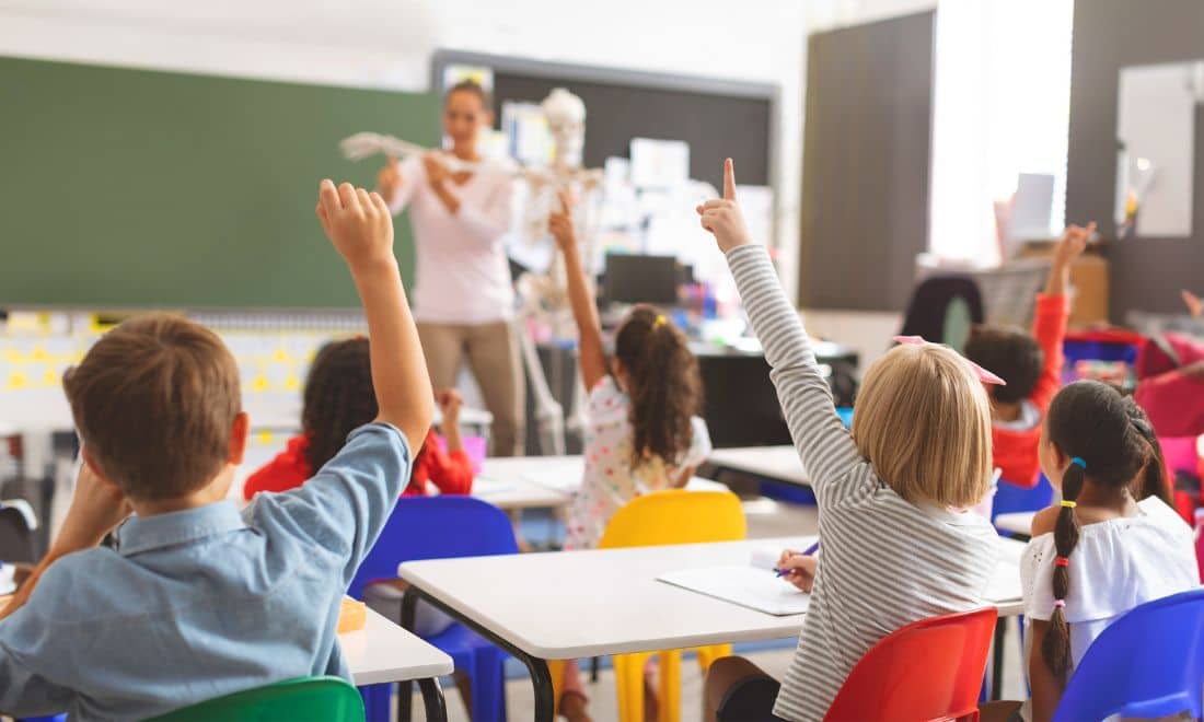 Escola turma professora na sala de aula com alunos com o dedo no ar