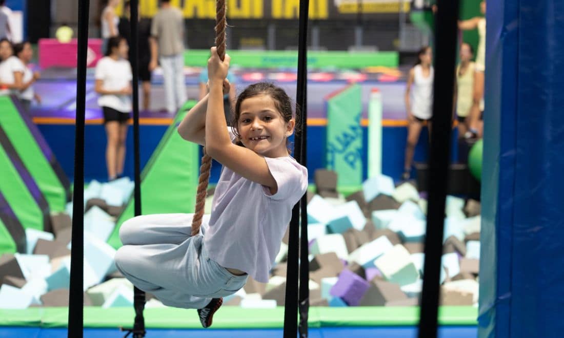 Quantum Park atividades para crianças menina a balançar numa corda piscina de esponjas atrás