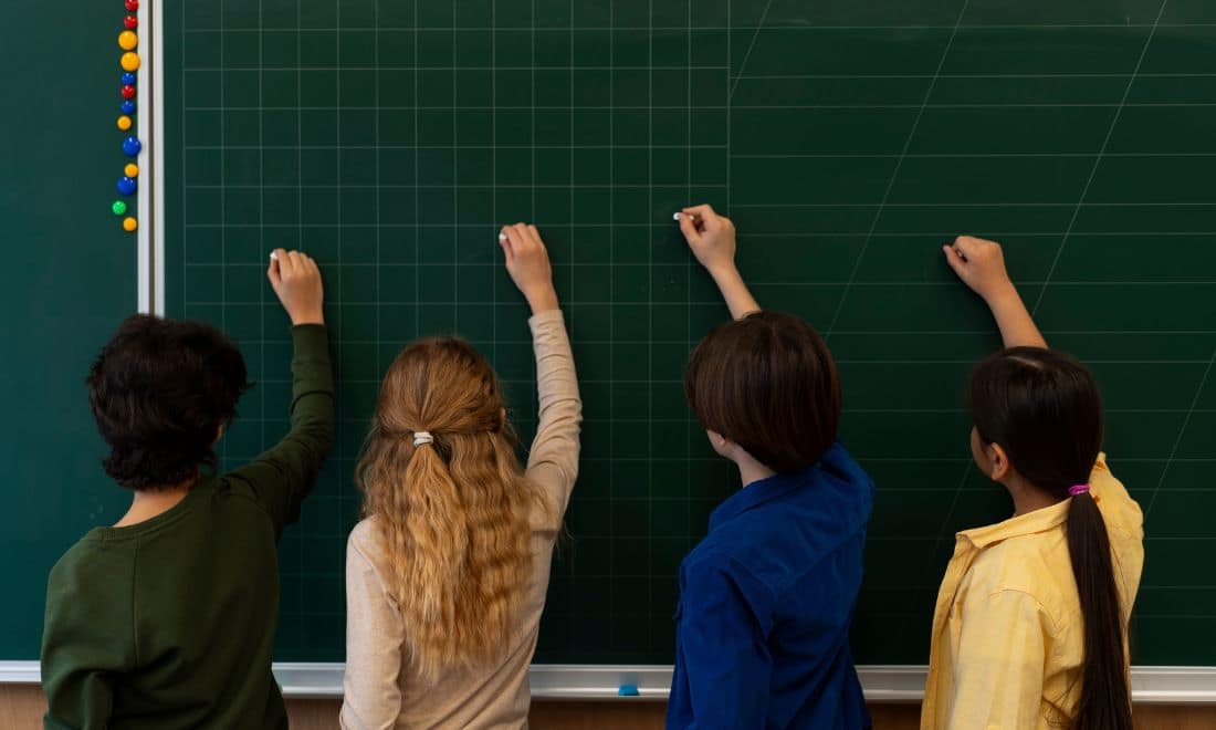 Escolas quatro crianças a escrever no quadro de giz