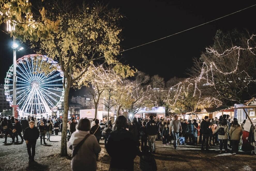 Barracas com várias pessoas e uma roda iluminada 