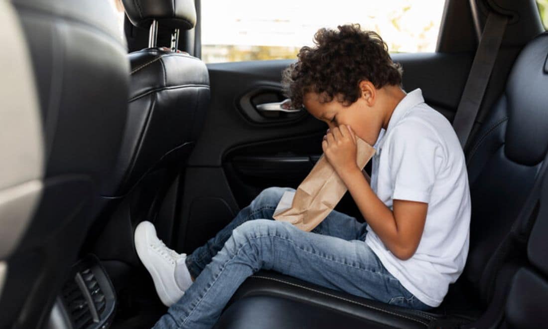 Viagens em família crianças enjoam menino enjoado com saco no banco de trás do carro