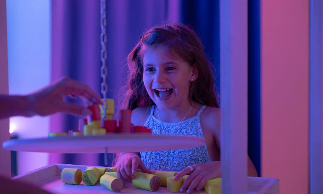 Museu Neonia menina surpreendida com jogo com peças de madeira luzes baixas neón