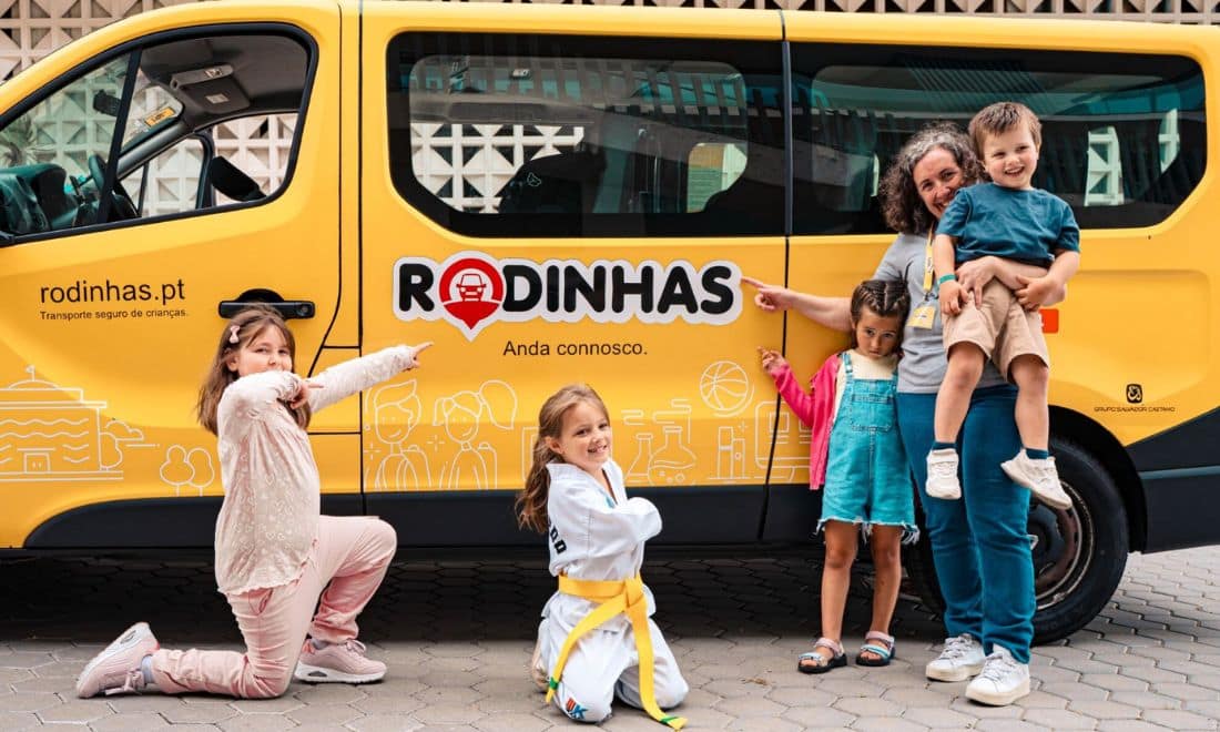 Rodinhas carrinha amarela com crianças ao lado e senhora apontar para o veículo
