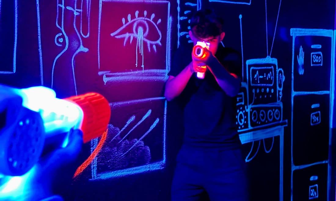 Quantum Park laser tag menino arma de laser nas mãos a fazer mira luzes neon