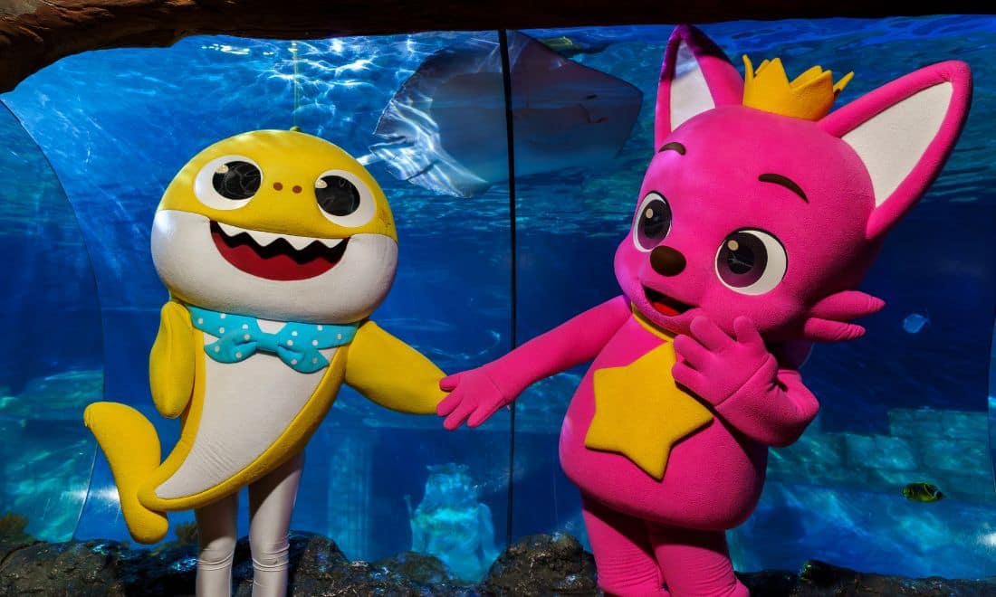 SEA LIFE Porto evento personagens BabyShark e raposa Pinkfong de mãos dadas em frente a um aquário