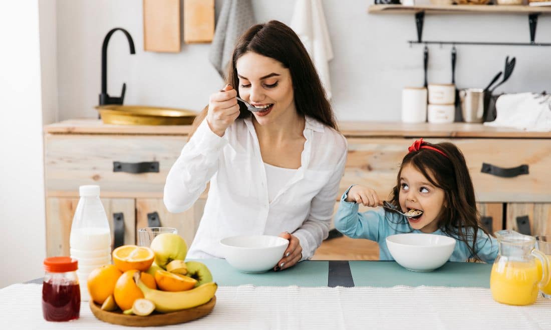 mãe e filha a comer uma refeição saudável em casa