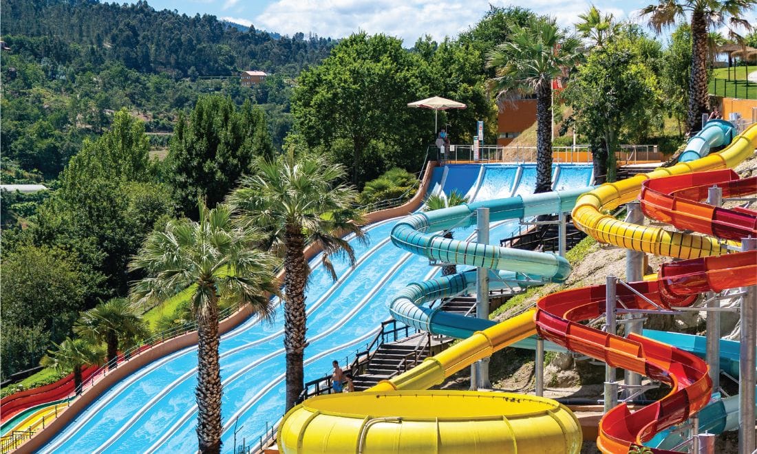 tubos de escorregas coloridos e palmeiras numa serra