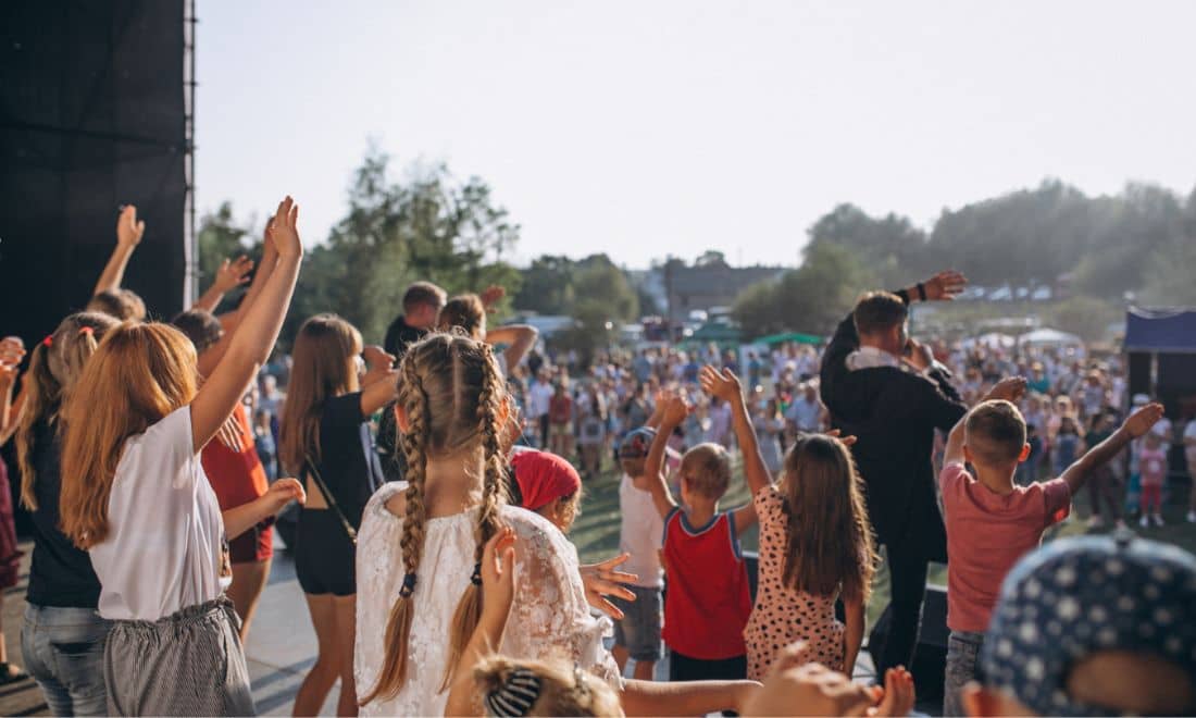 crianças e jovens de costas a ver um concerto numa multidão