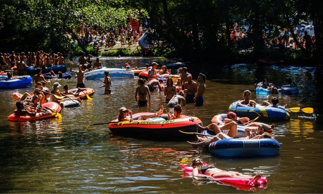 pessoas a boiar no rio coura com boias e vegetação
